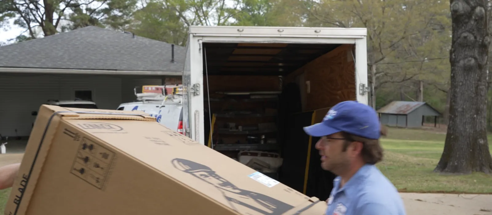 A Gilley's installer tips a boxed Lennox unit off the back of the trailer